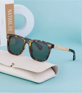 Detail of tortoiseshell square sunglasses with gold engraved temples on leather case