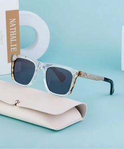 Close-up of square sunglasses with metal engraved temples and beige faux leather case