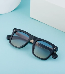 Detail view of square black sunglasses with gradient lenses and gold rivet accents