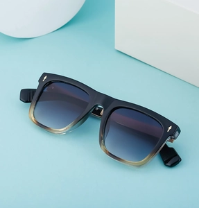 Detail of square sunglasses with blue-purple gradient lenses and gold arrow metal accents