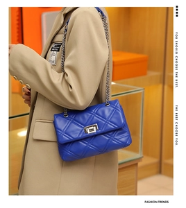 Close-up of a blue quilted leather chain bag with a silver rotating metal lock and strap