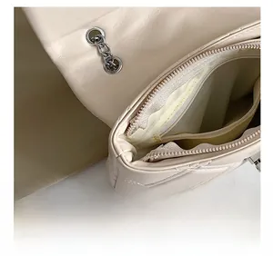 Detail view of the beige quilted shoulder bag showing interior zipper pocket and lining