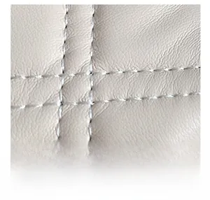 Macro shot of high-quality light grey faux leather with precise white cross-stitch patterns