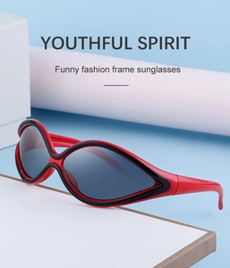 Close-up of red and black Y2K sports sunglasses with dark grey lenses on white props