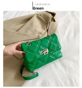 Detail of green quilted crossbody bag with silver rotating metal lock and chain strap