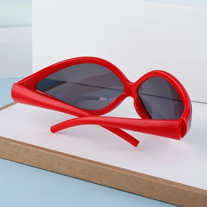 Detail of red oversized Y2K cycling sunglasses with bold curved frames and dark lenses