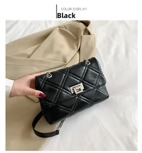 Detail of black quilted leather shoulder bag with silver metal square lock and chain