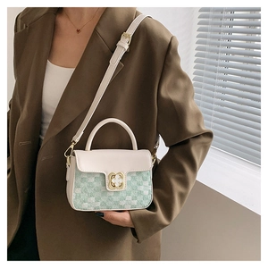 Detail of white leather and green tweed crossbody bag with clover-shaped gold buckle lock