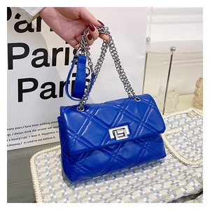 Detail of blue quilted PU leather handbag with silver metal twist lock and chain strap