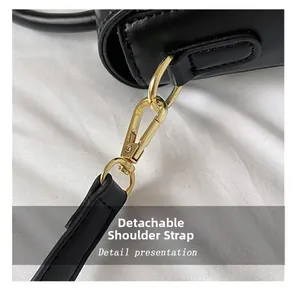 Close-up of detachable leather shoulder strap with gold-tone hardware on black handbag