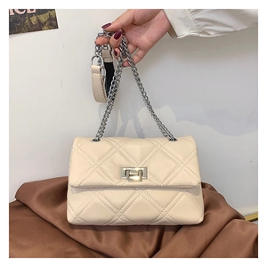 Detail of quilted beige chain bag featuring silver metallic twist lock and embroidery