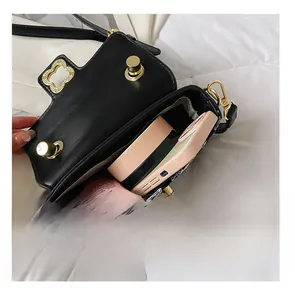 Detail view of the black crossbody bag showing its capacity for makeup and a smartphone