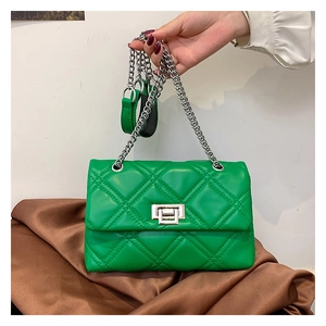 Detail of green quilted crossbody bag with silver chain strap and metal lock closure