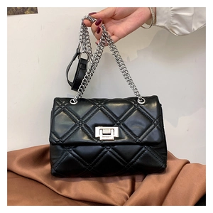 Close-up of black quilted crossbody bag with silver rotating lock and chain strap