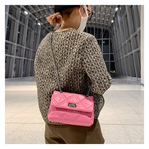 Close-up of pink quilted crossbody bag with silver chain strap and metal turn-lock closure