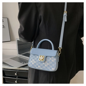 Detail of light blue crossbody bag with checkered fabric and gold clover clasp
