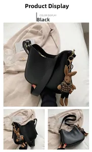 Detail view of black leather hobo bag featuring a cute bunny charm and wide shoulder strap