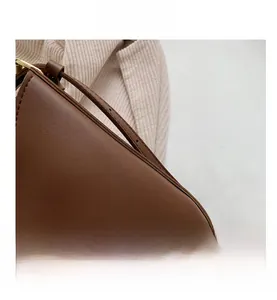 Close-up of matte brown leather tote bag with neat stitching and gold hardware detail