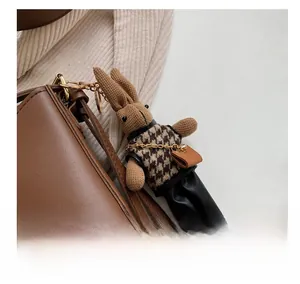 Close-up of a brown rabbit charm with houndstooth vest on a brown leather tote bag