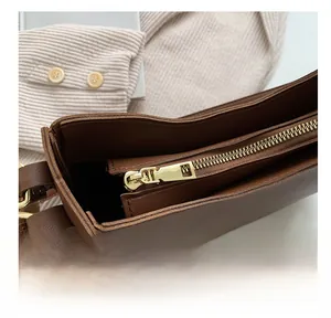 Detailed close-up of brown leather bag interior with premium gold metal zipper and stitching