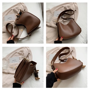 Detail view of brown vintage hobo bag with teddy bear charm and adjustable strap