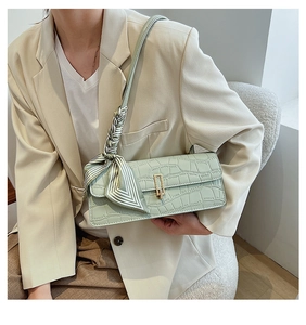 Détail du sac baguette vert menthe à motif crocodile avec foulard en soie sur la bandoulière