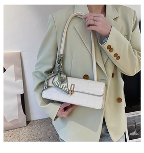 Détail du sac blanc texture crocodile avec boucle dorée et foulard en soie rayé vert