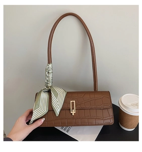 Détail du sac baguette marron à motif crocodile avec boucle dorée et foulard en soie
