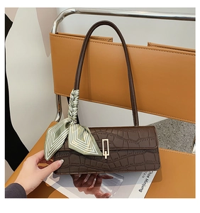 Détail du sac à bandoulière marron en cuir croco avec boucle dorée et foulard en soie