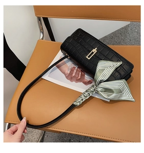 Détail du sac à bandoulière noir texture crocodile avec fermoir doré et foulard en soie