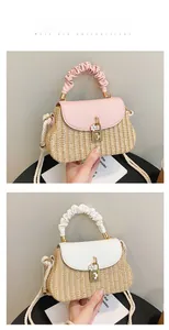 Detail of straw woven handbag with leather flap and floral charm on a crossbody strap