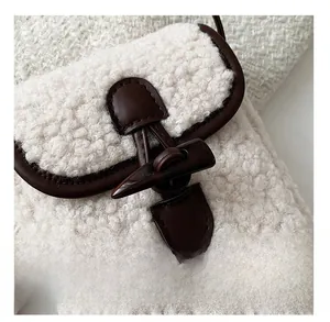 Detailed macro view of plush white faux shearling bag with dark brown leather horn buckle