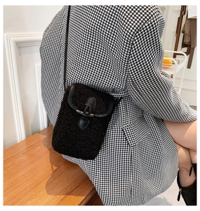 Detail of plush black crossbody bag with faux fur texture and leather buckle strap