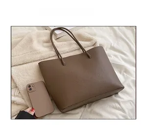 Size comparison showing the brown leather tote bag capacity relative to a smartphone