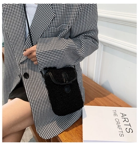 Detail of plush black crossbody phone bag with toggle closure on houndstooth blazer