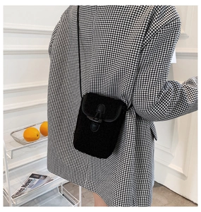 Detail of black faux shearling crossbody bag with horn buckle and leather piping trim
