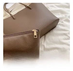 Detail of dark brown lychee pattern leather tote bag with gold metal zipper hardware