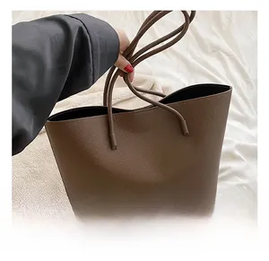 Detail shot of brown lychee grain leather tote bag with slender straps for commuting