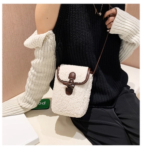 Detail of white faux shearling bag featuring brown leather trim and horn button closure