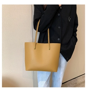 Close-up of mustard yellow leather tote bag with pebble texture and slim shoulder straps