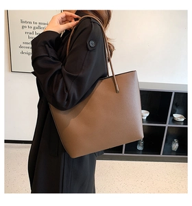 Detailed close-up of brown litchi pattern leather tote bag with dual shoulder straps