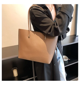 Close-up detail of light brown tote bag showing premium lychee grain texture and minimalist design