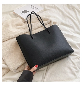 Detail of black pebbled leather tote bag with slender straps for daily commute use