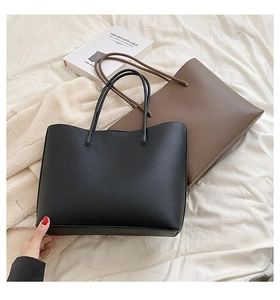 Close-up of black and brown lychee grain leather tote bags with long shoulder straps