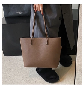 Brown lychee texture tote bag held by model featuring large capacity and thin straps