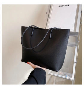 Close-up of black lychee grain tote bag showing premium leather texture and long straps