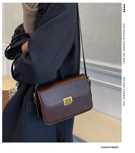 Detail of vintage brown leather crossbody bag with elegant golden square rotary lock