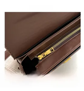 Detail view of smooth golden metal zipper on vintage brown leather crossbody bag