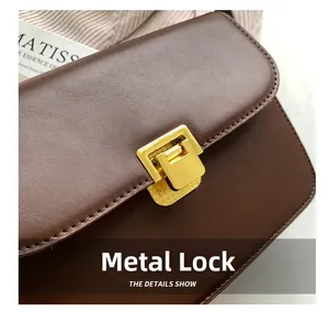 Detailed macro view of the premium golden square metal lock on a brown leather bag