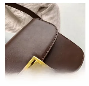 Close-up of brown leather bag showing meticulous stitching and gold square metal buckle